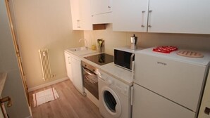 Eine kleine Küche mit Spüle, Mikrowelle, Backofen und Waschmaschine.