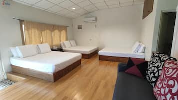 A hotel room with two beds, a sofa, and a wooden floor.