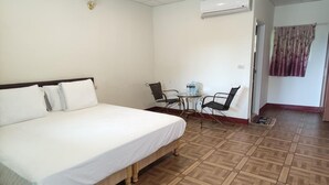 Ein Hotelzimmer mit einem großen Bett, einem kleinen Tisch mit Stühlen und einer Klimaanlage an der Wand.