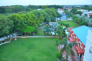 Un césped amplio y cuidado con una piscina y un edificio de techo rojo.