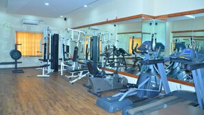 Un gimnasio con varios equipos de ejercicio, incluyendo cintas de correr, máquinas de pesas y un espejo grande.