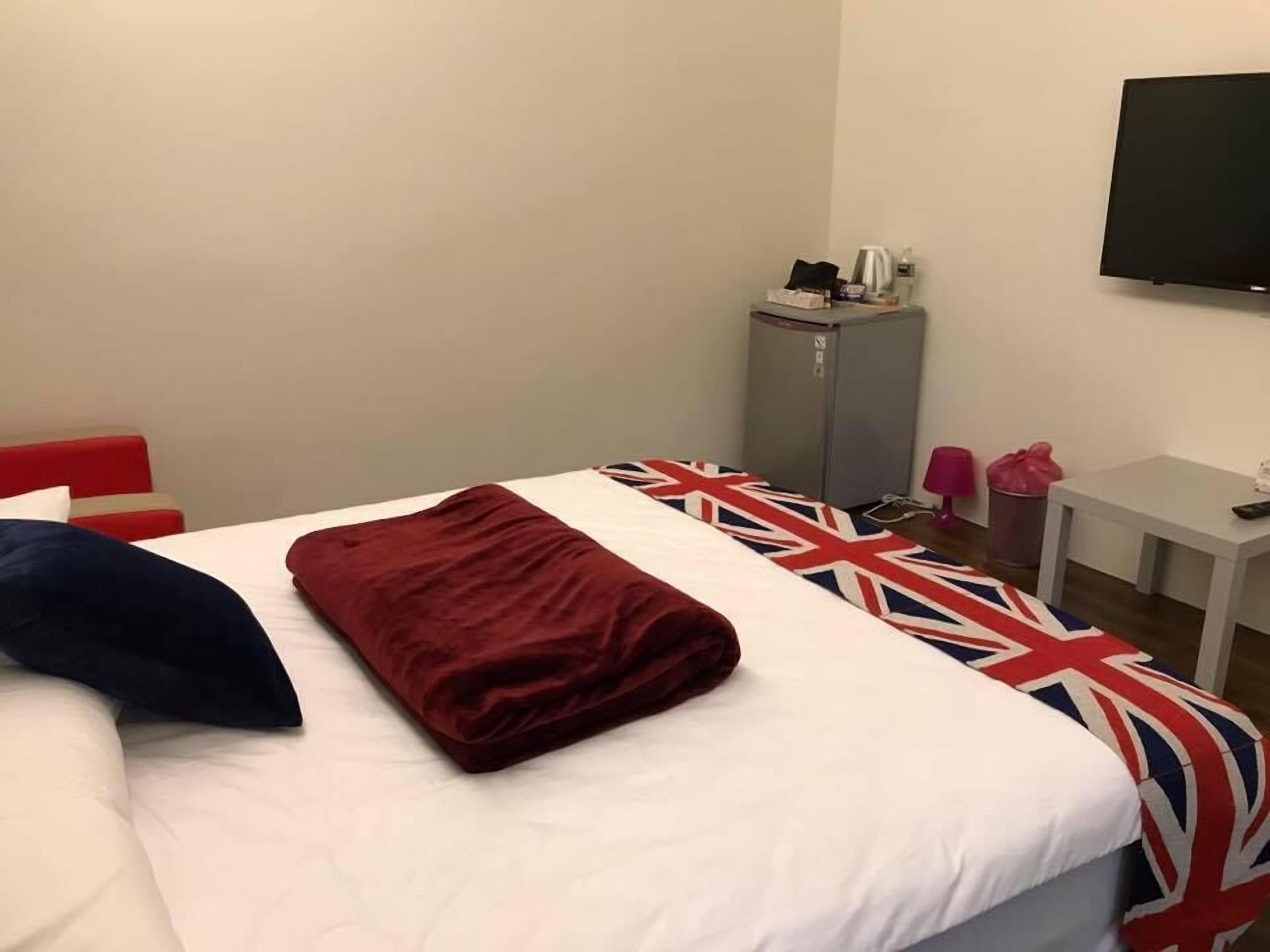 Ein Hotelzimmer mit einem Bett, einem kleinen Tisch, einem Fernseher und einem Schrank.