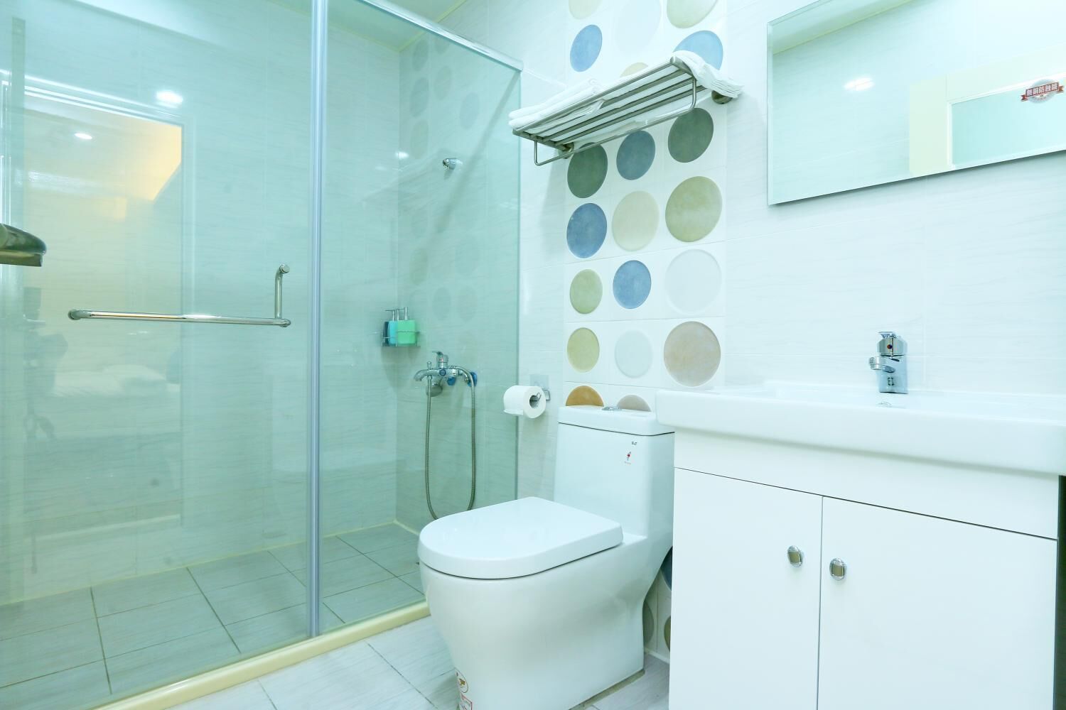 A modern bathroom with a glass shower enclosure, a toilet, and a sink with a mirror above.