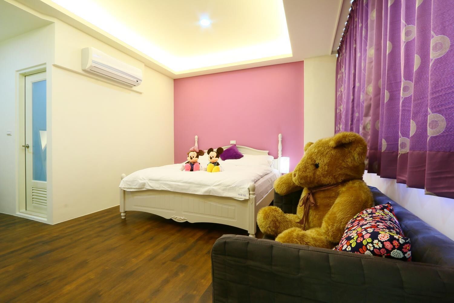 Un dormitorio con una cama, un oso de peluche y dos juguetes blandos sobre la cama.