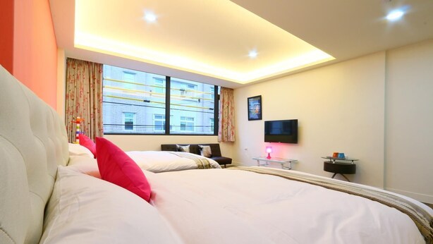 A hotel room with a large bed, a desk with a lamp, a flat-screen TV, and a window with curtains. - Chi Yu 85 (Ji'an)