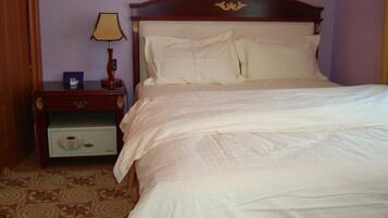 Una cama bien hecha con cabecera de madera, una mesita de noche con lámpara y una pequeña cómoda.