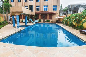 Una piscina al aire libre, sombrillas, sillones reclinables de piscina