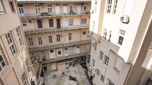 Ein mehrgeschossiges Wohngebäude mit Balkonen, einem Innenhof mit Topfpflanzen und einem Erdgeschoss mit einem Geschäft.