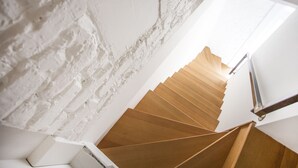 Eine Wendeltreppe mit Holzstufen und Metallgeländern, die zu einer weißen Tür führt.