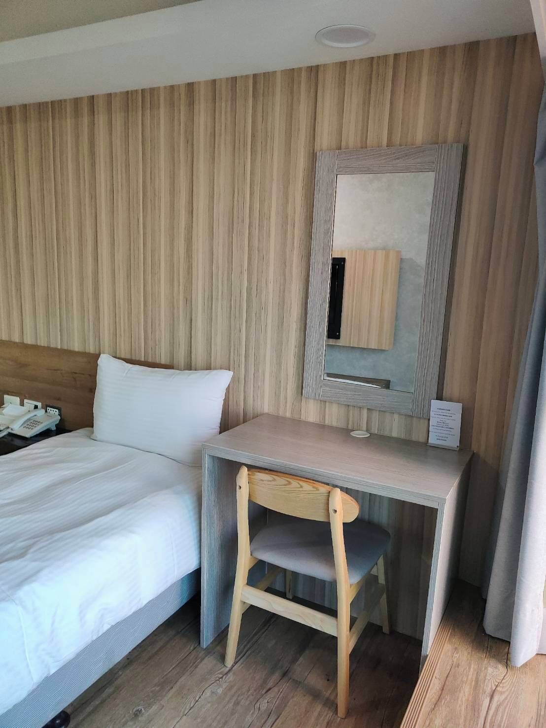 A hotel room with a bed, a desk, and a chair.
