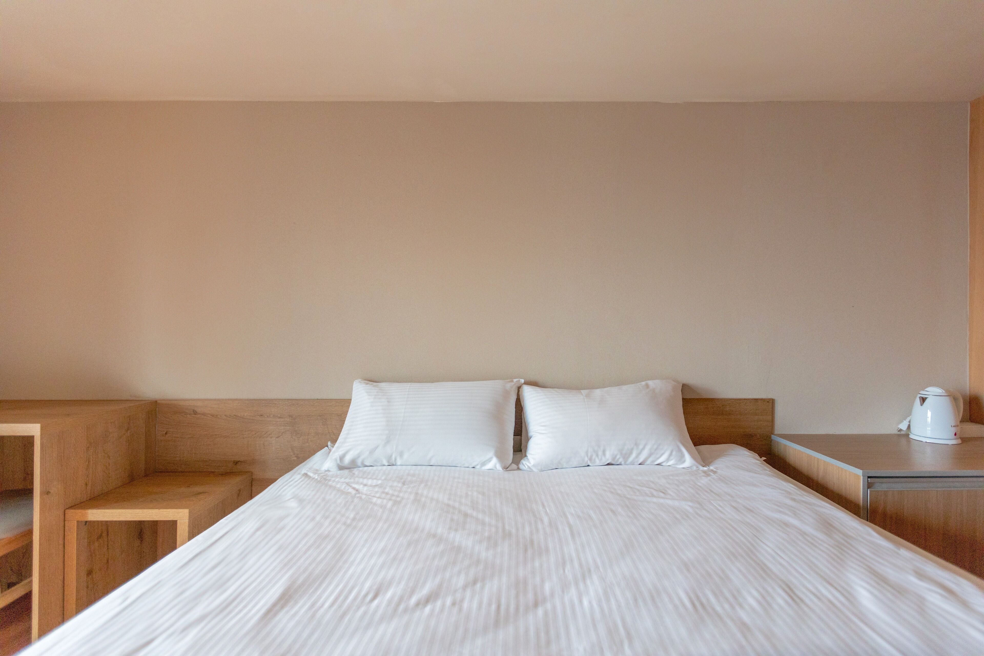 A neatly made bed with white linens in a hotel room.