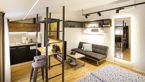 A compact living space with a kitchenette, a sofa, a coffee table, and a mirror. - Atomic Apartment 02 (Belgrade)