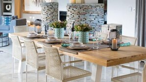 A dining area with a wooden table set for six, surrounded by wicker chairs.