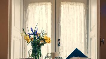A dining area with a table set for two, a vase of flowers, and a pitcher.