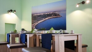 A dining area with a view of a coastal landscape, wooden furniture, and a table set with cups and a teapot. - Kapsott B&B (Bisceglie)