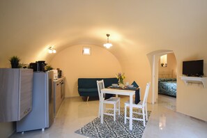 Un espacio habitable compacto con kitchenette, zona de comedor, sofá y televisor.