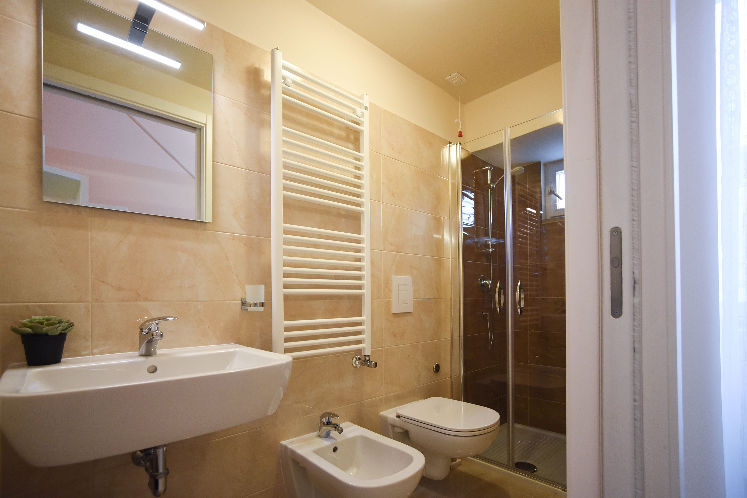A bathroom with a sink, bidet, and glass shower enclosure.