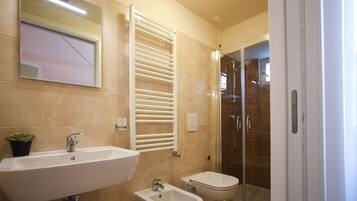 A bathroom with a sink, bidet, and glass shower enclosure.