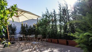 An outdoor patio with a large umbrella, folding chairs, and a table. - Kapsott B&B (Bisceglie)