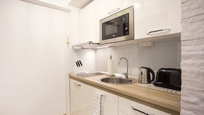 Een kleine keuken met een magnetron, spoelbak en waterkoker.