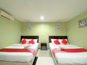 Une chambre d’hôtel avec deux lits, chacun doté de draps rouges et blancs, une petite table et deux ventilateurs fixés au mur.