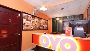 A reception desk with a large 'OYO' sign, a wall-mounted fan, and a framed photo collage. - Hotel O Bamboo Inn (George Town)