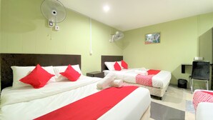 A hotel room with two beds, each with red and white bedding, and a single bed with a red and white blanket. There are two wall-mounted fans and a small table with a chair. - Hotel O Bamboo Inn (George Town)
