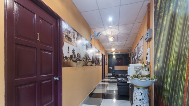A hotel hallway with a checkered floor, a large door on the left, and a decorative wall with photographs. - Hotel O Bamboo Inn (George Town)