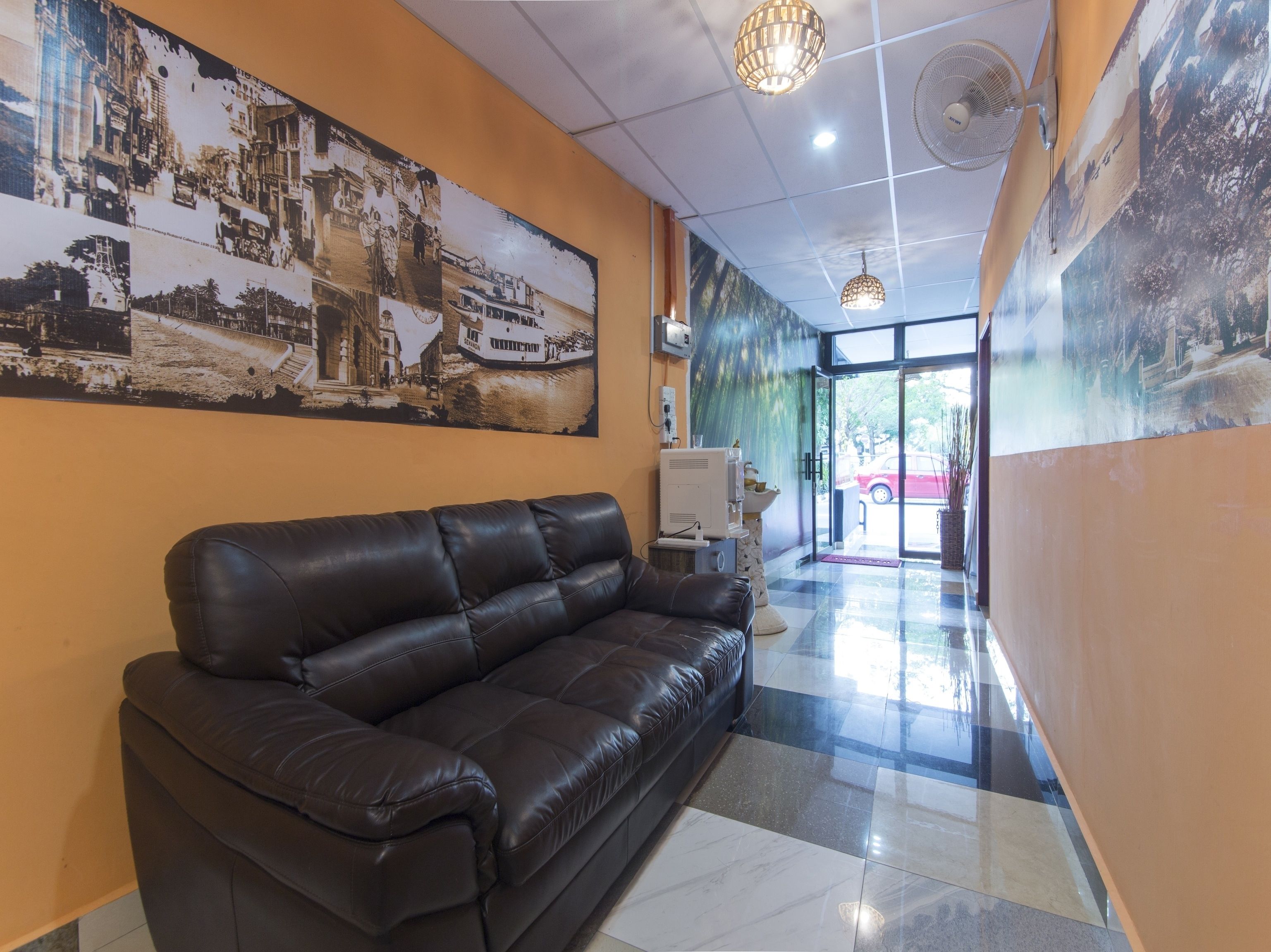 A reception area with a black leather sofa, a wall-mounted TV, and a large poster of a historical building.