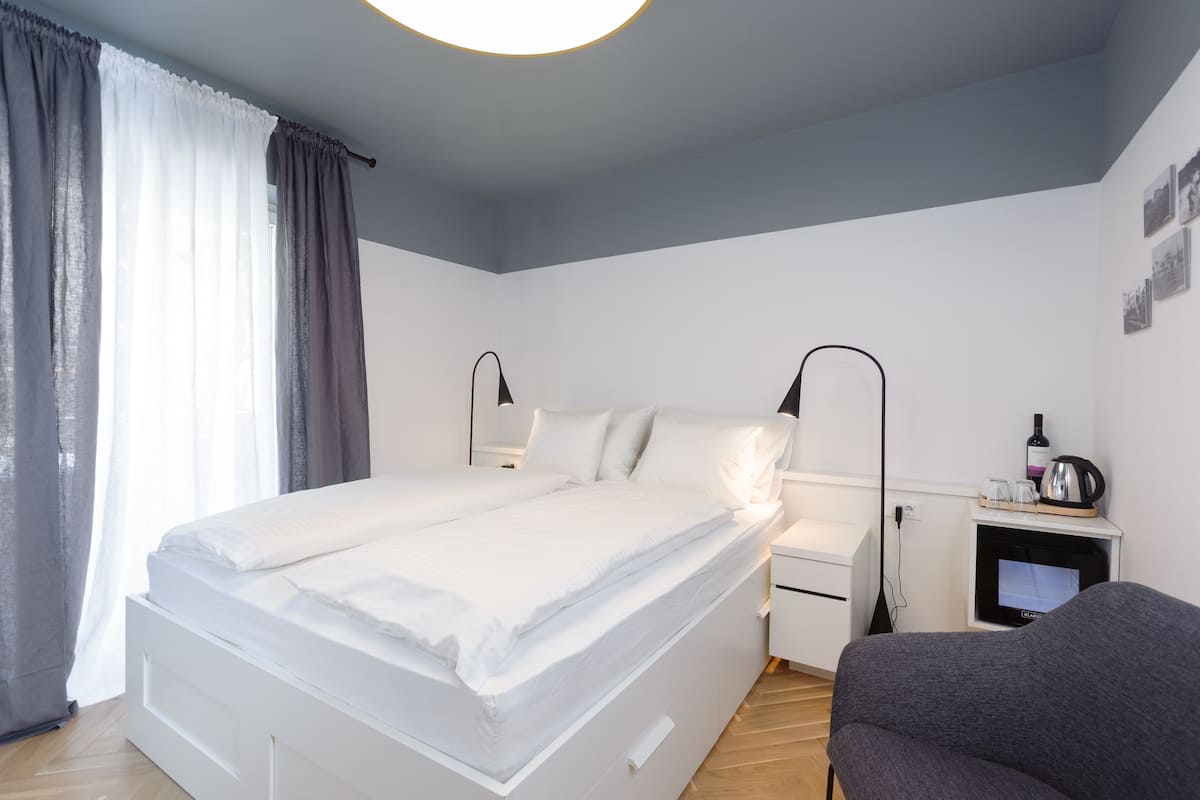 A modern bedroom with a large bed, bedside tables, a TV, and a chair.
