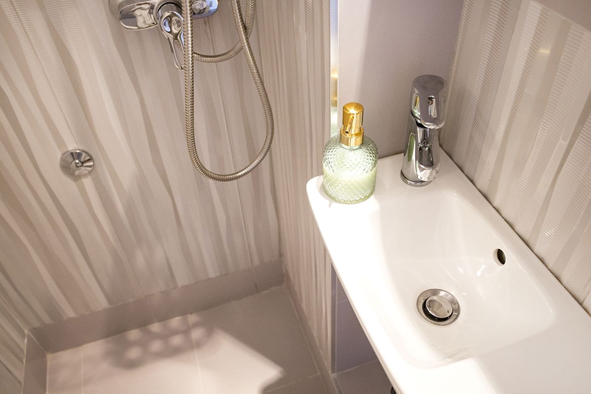 Un baño con ducha, lavabo y una botella de jabón.