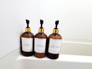 Three bottles of bathroom products on a shelf. - Floria Namba (Osaka)