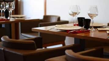 A restaurant setting with tables set for dining, each with a wine glass and cutlery.