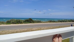 A view of the ocean with birds flying overhead, a road in the foreground, and a person standing by the railing. - Unique Ocean Front Beach House (Flagler Beach)