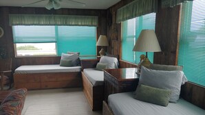 A cozy cabin-style room with two wooden beds, a bench, and a table. - Unique Ocean Front Beach House (Flagler Beach)