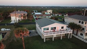 A residential area with houses, including a two-story building with a balcony and a single-story house with a red car parked in front. - Unique Ocean Front Beach House (Flagler Beach)