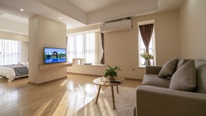 Een moderne woonkamer met een bank, een televisie, een salontafel en een bed met uitzicht op de omgeving.