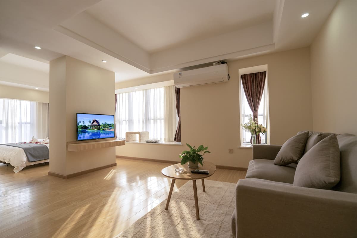 Un salon moderne comprenant un canapé, un téléviseur, une table basse et un lit donnant sur l’extérieur.