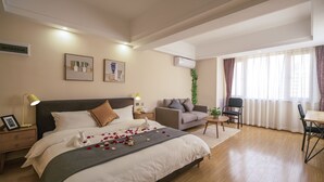 Een hotelkamer met een groot bed, een bank, een eettafel en een klein bijzettafeltje.