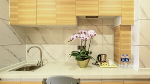 Een moderne keuken met houten kastjes, een marmeren achterwand, een roestvrijstalen spoelbak en een potorkidee, plus een koffiezetapparaat.