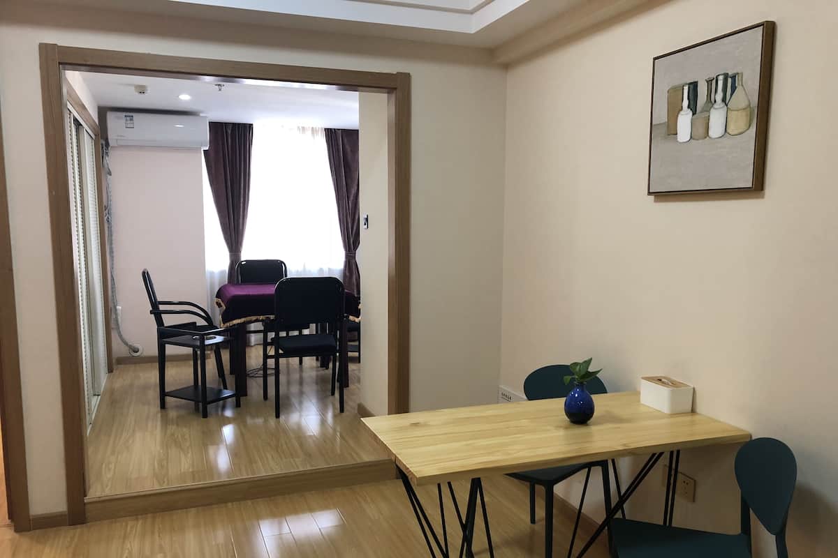 Une pièce avec un plancher en bois, une table à manger avec des chaises, un vase bleu et une œuvre d’art encadrée accrochée au mur.