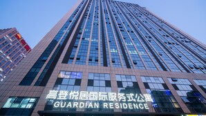 Een hoog gebouw met een bord waarop 'GUARDIAN RESIDENCE' staat.