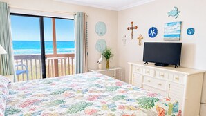 A bedroom with a bed, a television, a small table, and a view of the ocean. - Experience Tilghman Beach and Racquet Club Unit 207! Oceanfront, Pools, Tennis, Close to Main Street! (North Myrtle Beach)