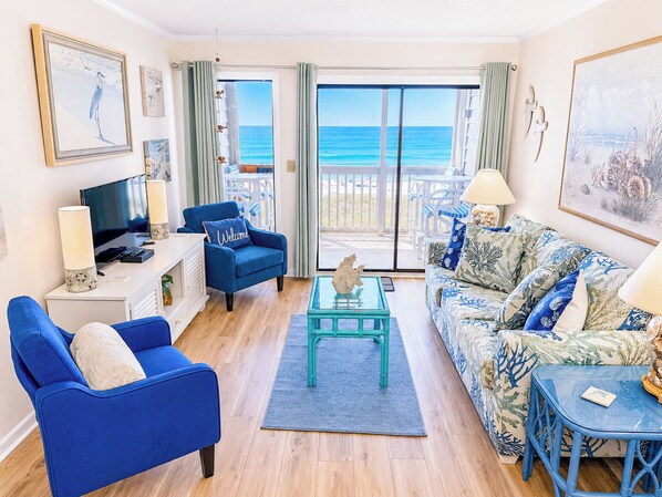 A living room with a sofa, armchair, coffee table, and a television. - Experience Tilghman Beach and Racquet Club Unit 207! Oceanfront, Pools, Tennis, Close to Main Street! (North Myrtle Beach)
