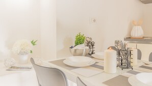 A dining area with a white table set for four, including plates, cutlery, and candles. - Pretty Home (Varenna)