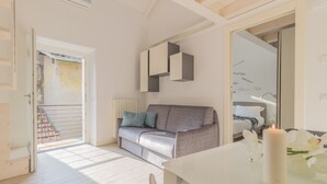 A modern living room with a grey sofa, a white table, and a lit candle. - Pretty Home (Varenna)