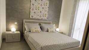 Ein Schlafzimmer mit einem Bett, zwei Nachttischen und einem an der Wand hängenden Kunstwerk.