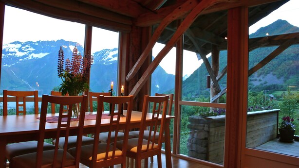 A wooden dining table with chairs, a vase with flowers, and a candle. - Magnificent landscape, fjords and mountains and an unic sommer house. (Norangsfjorden)