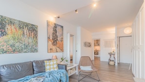 A modern living room with a leather sofa, a coffee table, and a chair. There are two paintings on the wall and a door leading to another room. - The Apple House (Varenna)