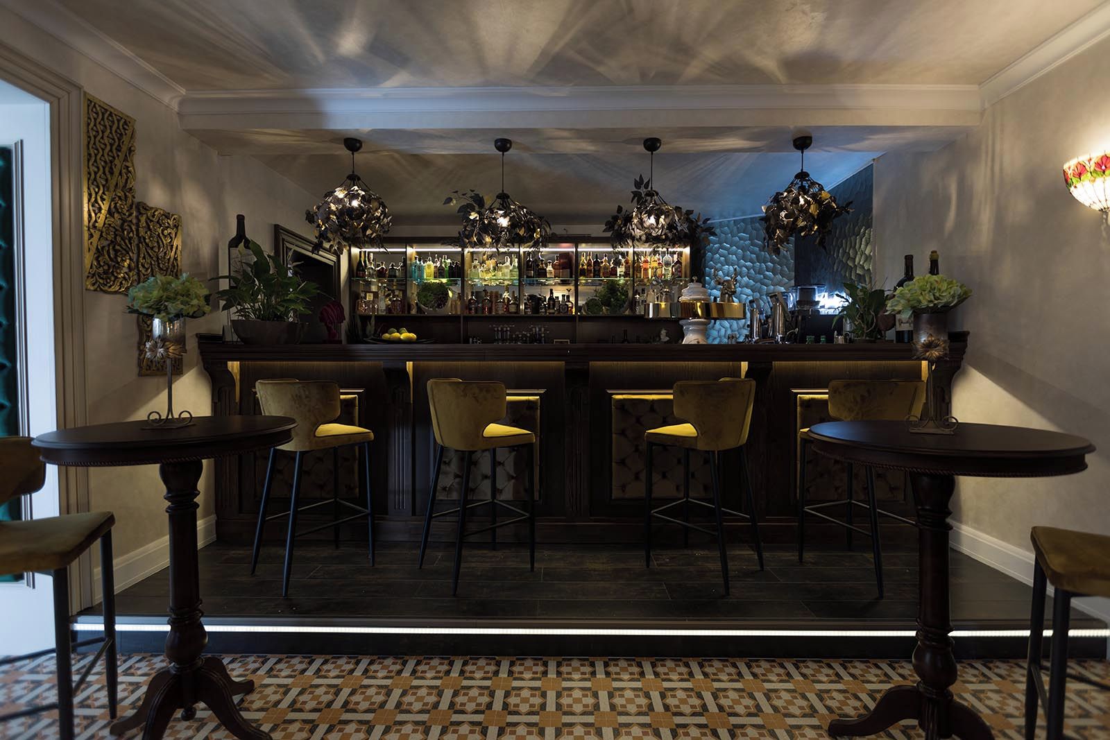 A bar area with a counter, bar stools, and a patterned floor.